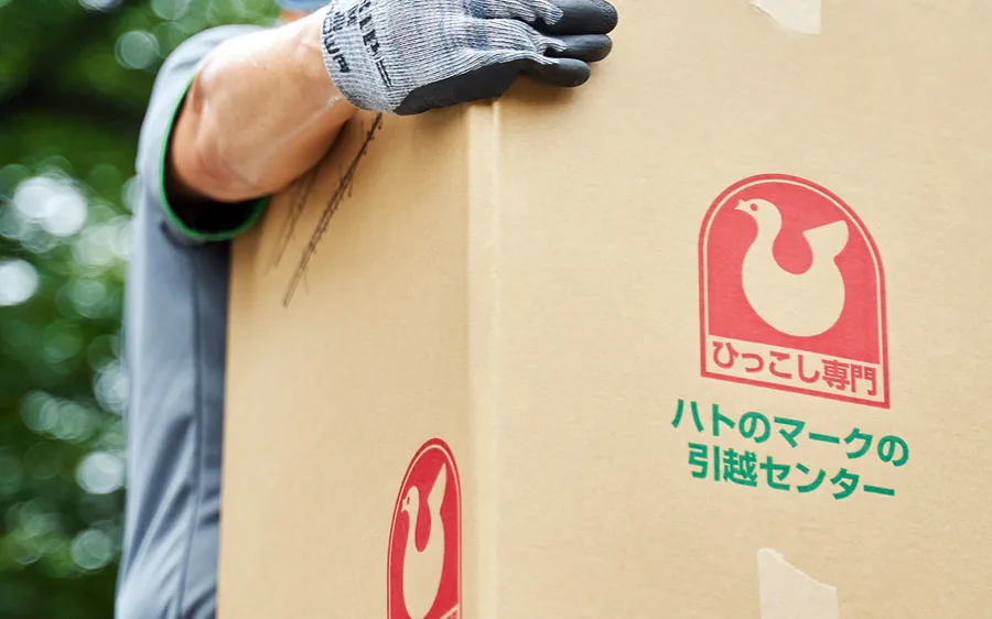 ハトのマークの専用資材で家財をていねいに扱う作業スタッフの手元