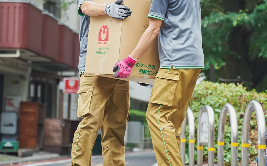 ハトのマークの引越センターの制服で家財を運ぶ作業スタッフ