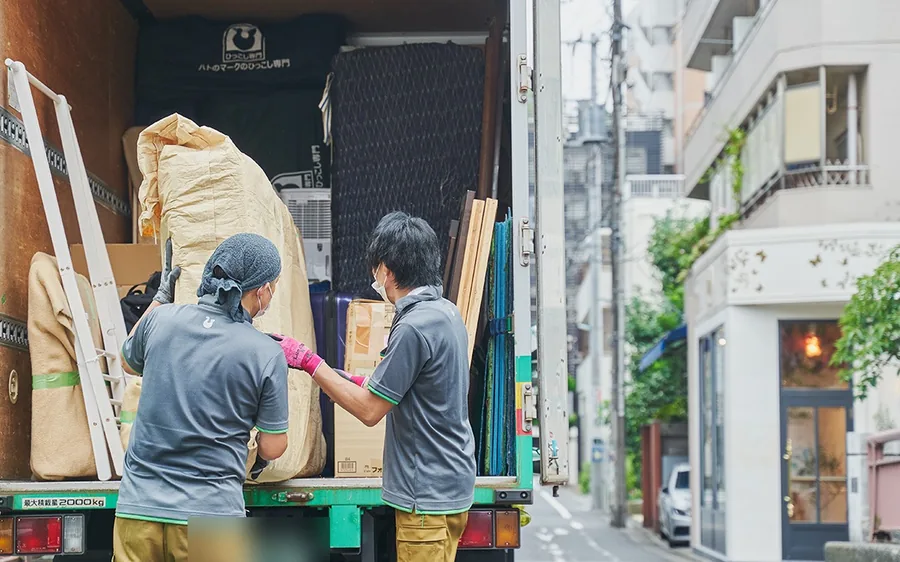 ハトのマークの引越センターの制服でトラックへ家財を積み込む作業スタッフ